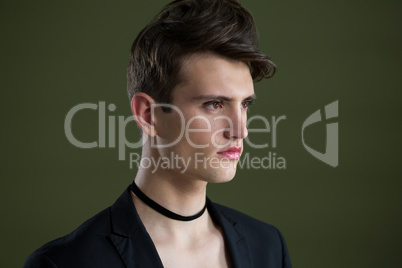 Androgynous man looking sideways against green background