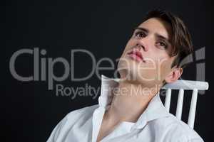 Androgynous man posing while sitting on chair