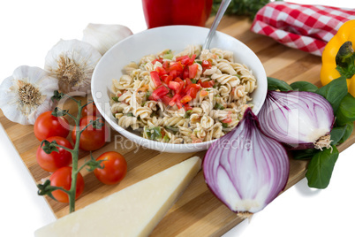 Pasta served in bowl amidst vegetables on cutting board