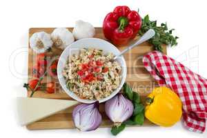 Overhead view of pasta served in bowl amidst vegetables on cutting board