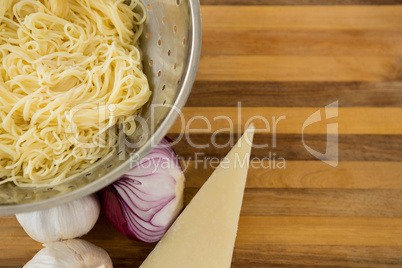 Overhead view of pasta in colander with ingredients