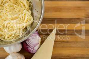 Overhead view of pasta in colander with ingredients