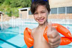 Young boy showing thumbs up at poolside