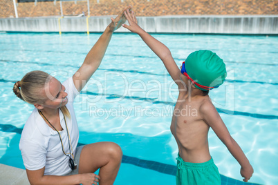 Female trainer training a boy for swimming