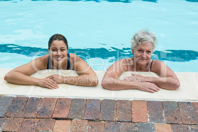 Female coach and senior woman leaning on poolside