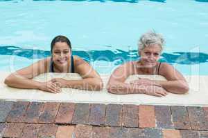 Female coach and senior woman leaning on poolside