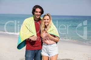 Young couple wearing towel while standing at beach