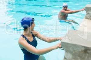 Senior man interacting with woman at poolside