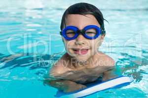 Smiling boy with swim goggles swimming in the pool