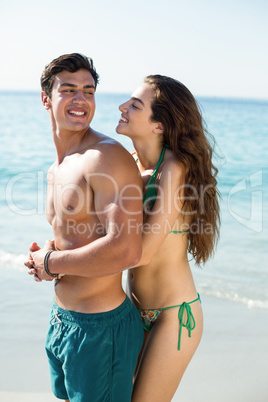 Woman embracing happy boyfriend at beach