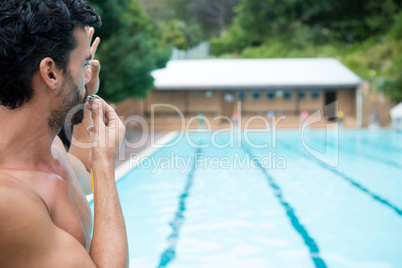 Lifeguard looking at swimming pool and blowing whistle