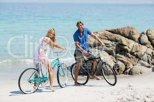 Portrait of couple riding bicycles at beach