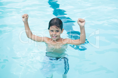 Young boy standing with arms up in pool