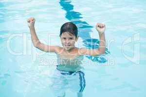 Young boy standing with arms up in pool