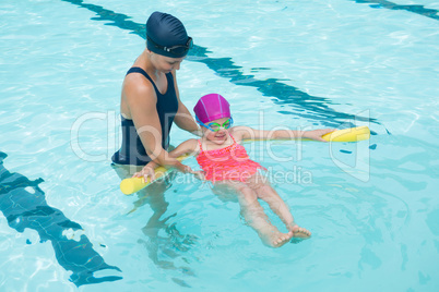 Female instructor training young girl in pool