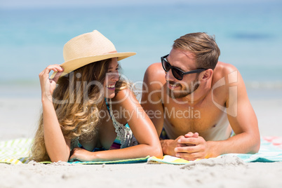 Couple lying on sand at beach during sunny day