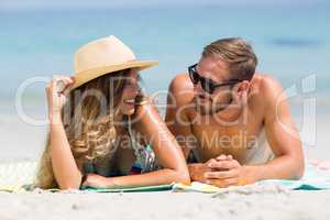 Couple lying on sand at beach during sunny day
