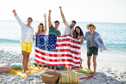 Friends holding American flag while standing on shore