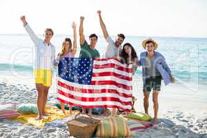 Friends holding American flag while standing on shore