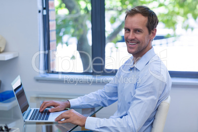 Portrait of smiling dentist working on laptop