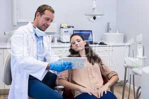 Dentist discussing over digital tablet with female patient