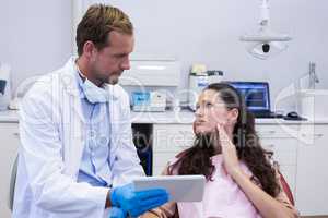 Dentist discussing over digital tablet with female patient