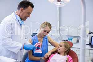 Dentist showing young patient how to brush teeth