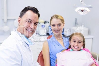 Portrait of dentist with young patient and his mother