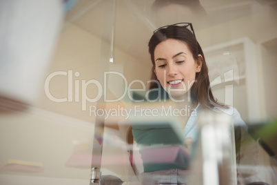Smiling woman using tablet while sitting at glass table