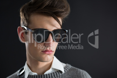 Androgynous man in sunglasses posing against black background