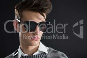 Androgynous man in sunglasses posing against black background
