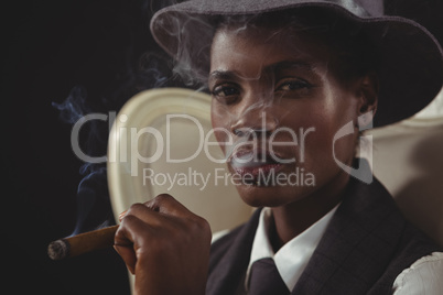 Androgynous man smoking cigar while sitting on a chair