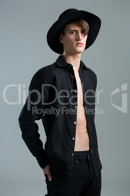 Androgynous man in hat posing with hands in his back pocket