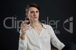 Androgynous man posing while holding spectacles