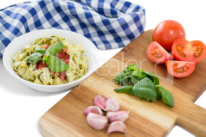 Vegetables on cutting board by pasta and napkin