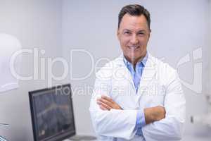 Portrait of happy dentist standing with arms crossed