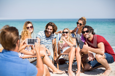 Man photographing cheerful friends at beach