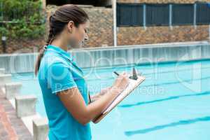 Female coach writing on clipboard