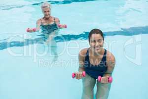 Female coach and senior woman exercising with dumbbells