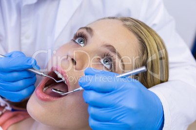 Dentist examining a female patient with tools