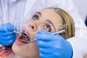 Dentist examining a female patient with tools