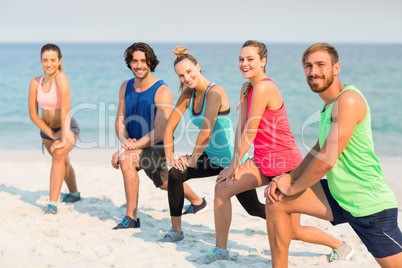 Friends stretching on shore at beach