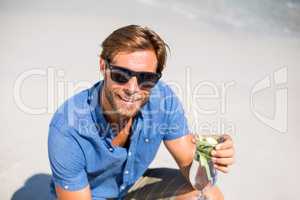 Young man having drink at beach during sunny day