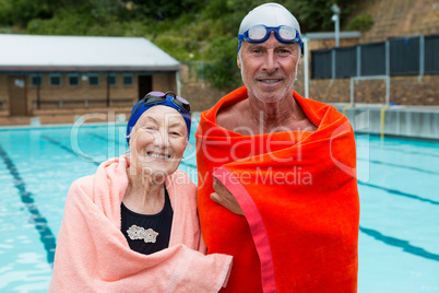 Senior couple wrapped in towel at poolside