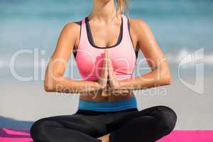 Woman meditating while sitting at beach