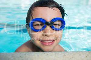 Smiling boy with swim goggles swimming in the pool