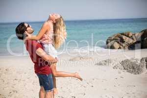 Happy boyfriend carrying girlfriend while standing at beach