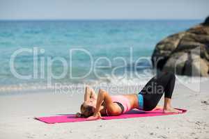 Woman exercising on exercise mat at beach