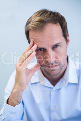 Portrait of tensed dentist sitting with hand on forehead