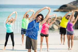 Friends exercising while standing on shore